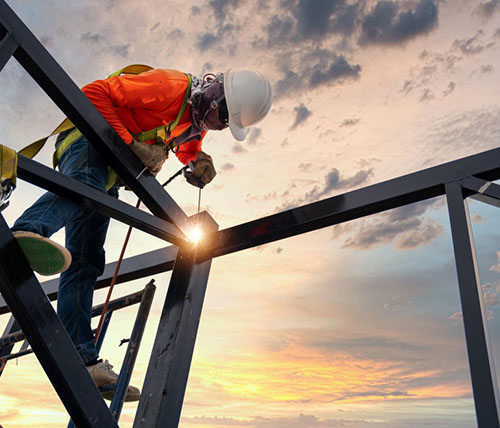 Welder working on construction site at sunset