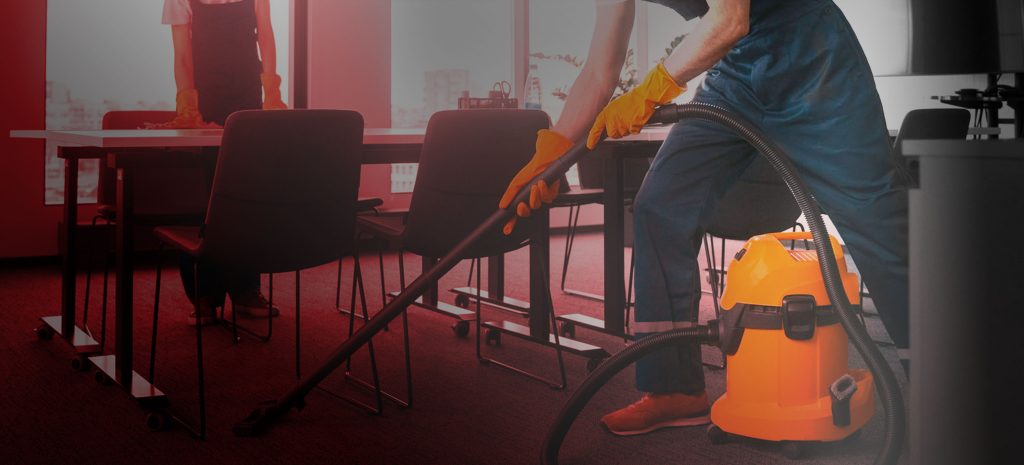 Professional cleaners vacuuming office carpet—commercial cleaning service with safety gear and modern equipment.